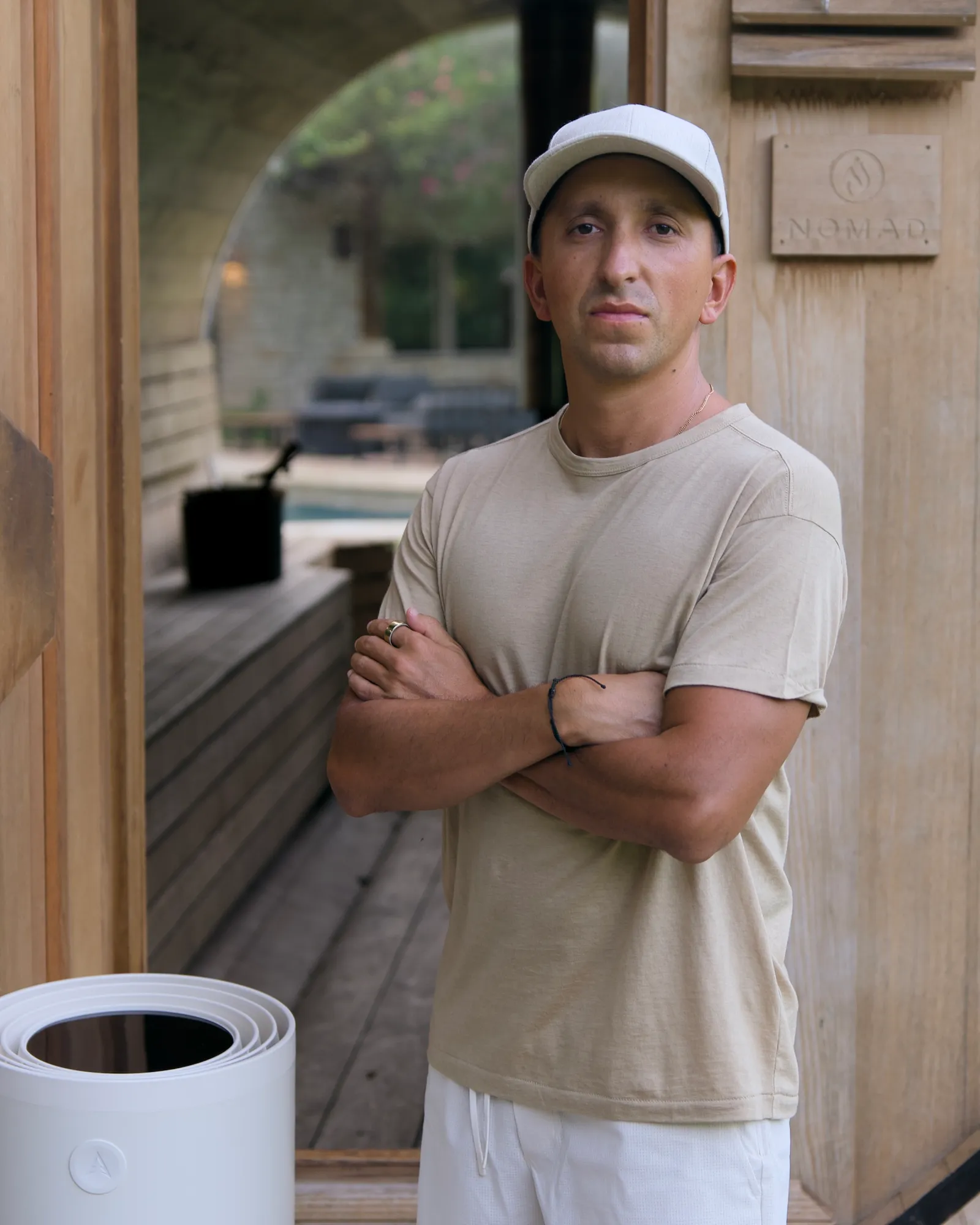 Kyle Lasota standing at the door of his home barrel sauna, arms crossed